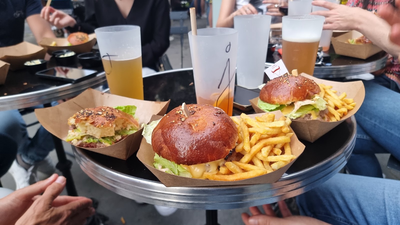 Trois burgers avec frites servis sur plateau argenté dans un restaurant