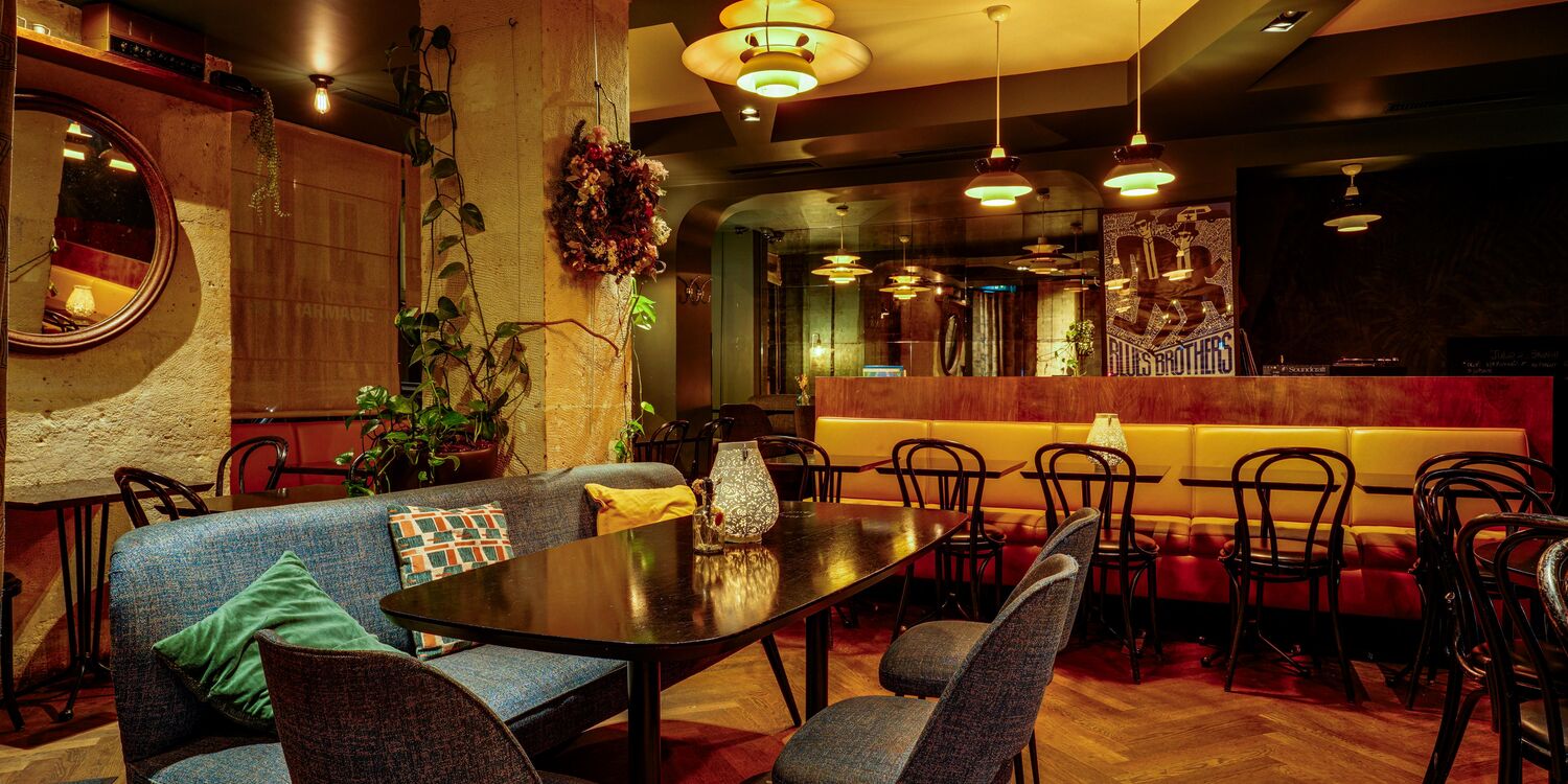 Salle de restaurant chaleureuse avec canapés bleus, éclairage tamisé et décoration vintage